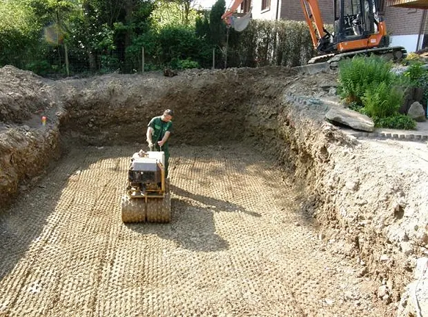 Verdichten der Poolgrube mit Rüttelplatte auf Schotterschicht