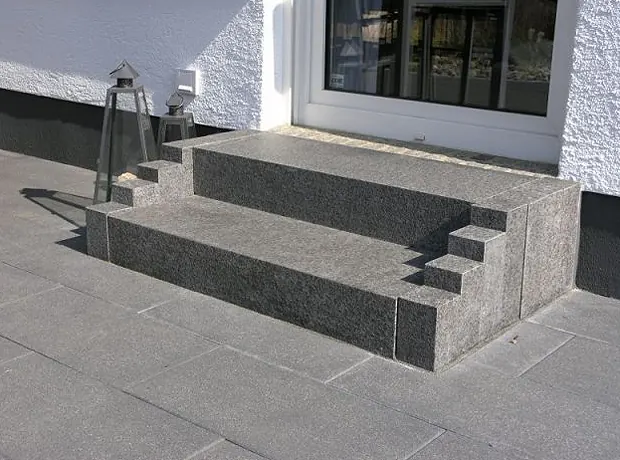 Hauseingang mit Granitblockstufen vor einer Terrassenfläche