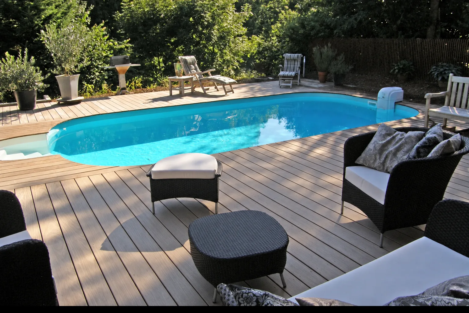 Poolanlage mit Sonnendeck aus Holz, Loungemöbeln und Olivenbäumen in einem Hausgarten